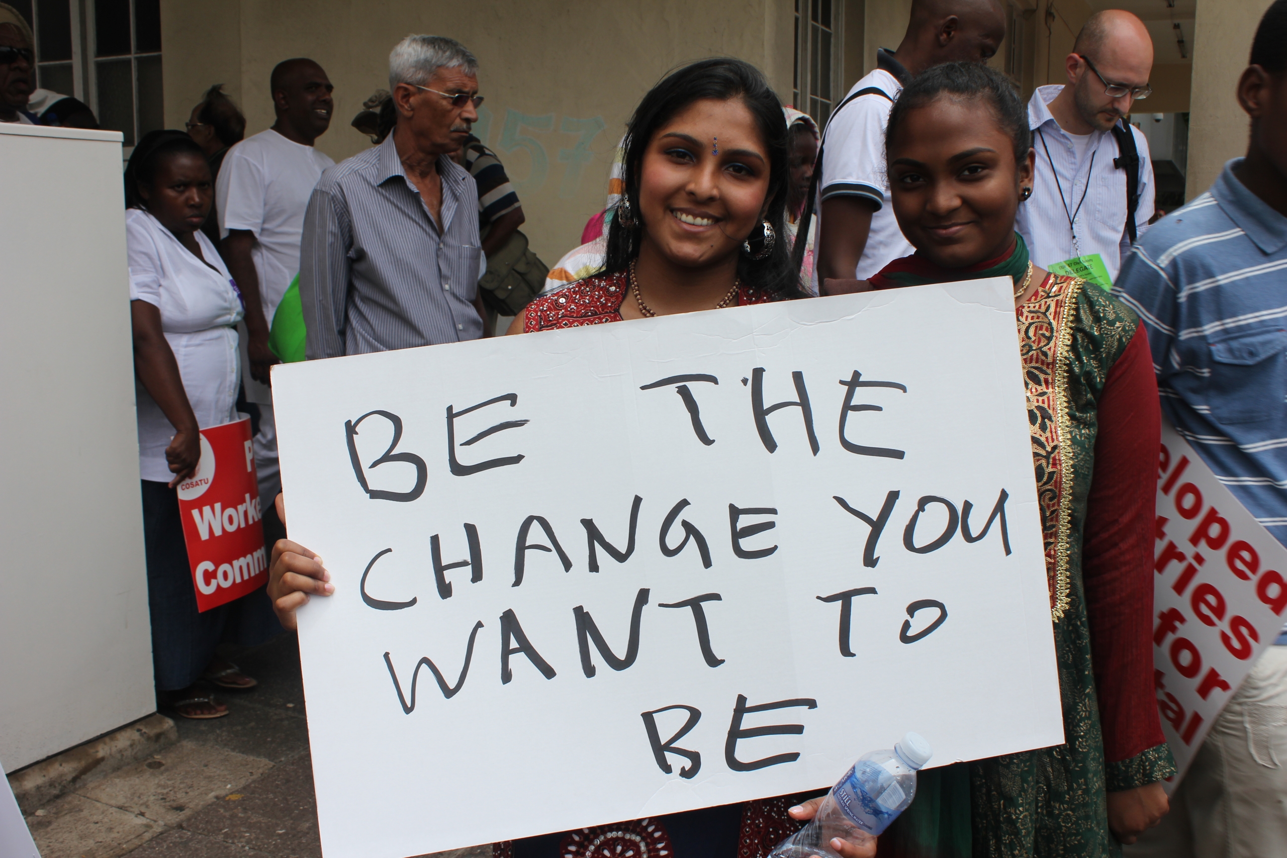 Two adolescents in Durban, South Africa hold a sign that reads "BE THE CHANGE YOU WANT TO BE" during a climate change protest.